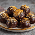 Easy & Healthy Pumpkin Truffles – A Guilt-Free Fall Dessert 7 Healthy pumpkin truffles with chocolate coating and nut topping on a serving plate.