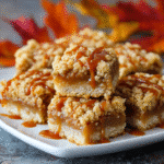 Easy Salted Caramel Apple Crumble Bars Recipe 7 Salted Caramel Apple Crumble Bars on a white plate with caramel drizzle.